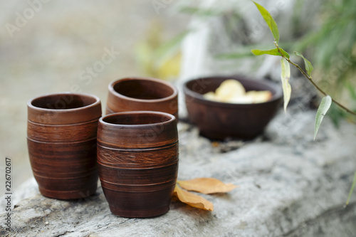 clay cups with tea on a wooden log in the autumn forest among the leaves