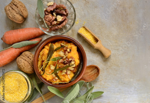 Corn porridge / polenta / with roasted carrots, walnuts and sage, top view, copy space
