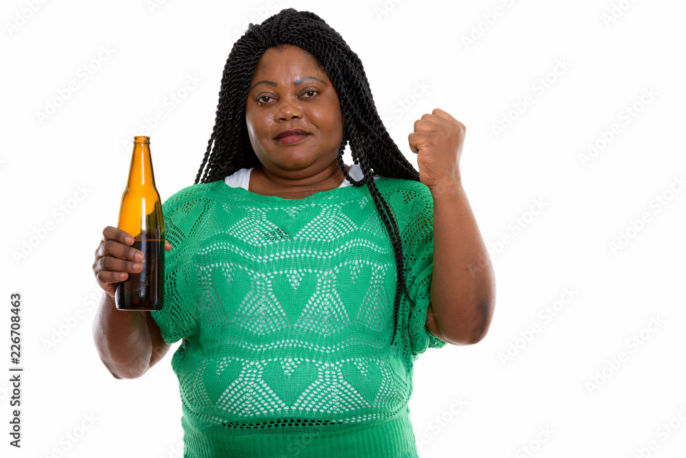 Studio shot of fat black African woman holding bottle of beer an