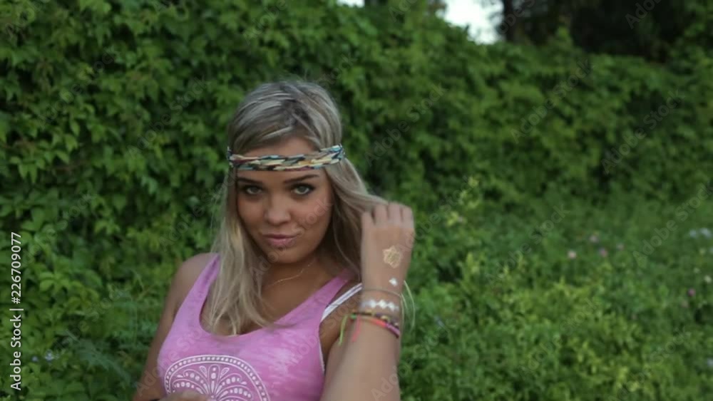 Young hippie woman turns around, looks at camera and smiles on background of green landscape. Young hippie woman turns around, looks at camera and smiles on background of green landscape.