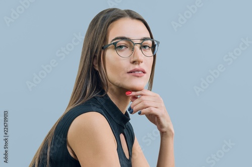Fotografija Portrait of young attractive woman with glasses close-up, on blue background, co