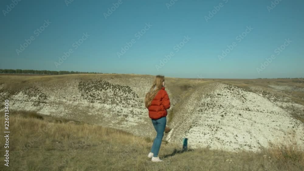 Young beautiful girl makes photos of the surrounding landscape. Girl you are a hill. Sunny day. Rest and travel. Young beautiful girl makes photos of the surrounding landscape. Girl you are a hill. Sunny day. Rest and travel.