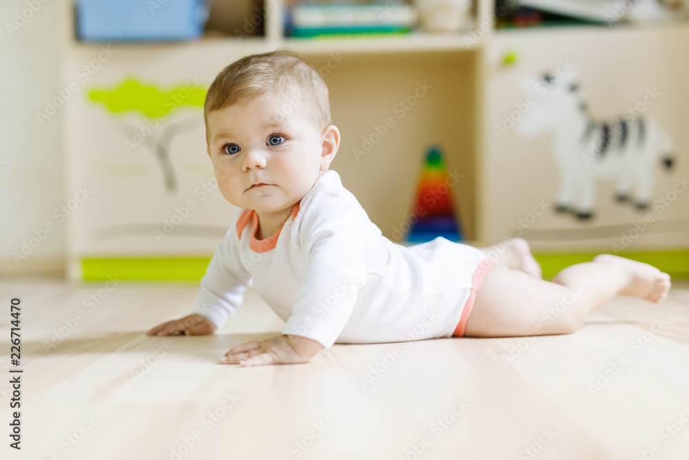 Fototapeta premium Cute baby girl learning crawling and sitting in children room