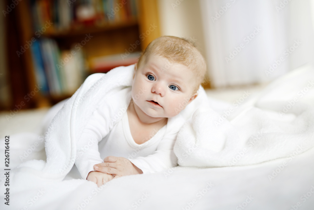 Baby girl wearing white towel or winter overal in white sunny bedroom Baby girl wearing white towel or winter overal in white sunny bedroom