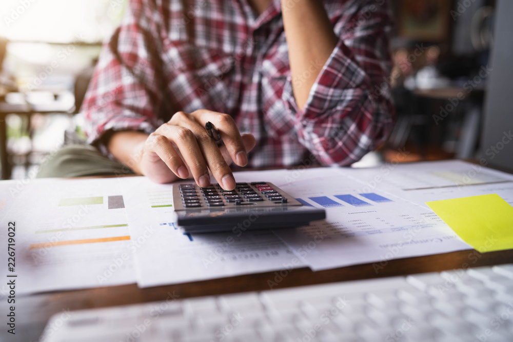 Businessman hand working with finances about cost and calculator on white desk in office. Businessman are using hands press calculator. Businessman hand working with finances about cost and calculator on white desk in office. Businessman are using hands press calculator.