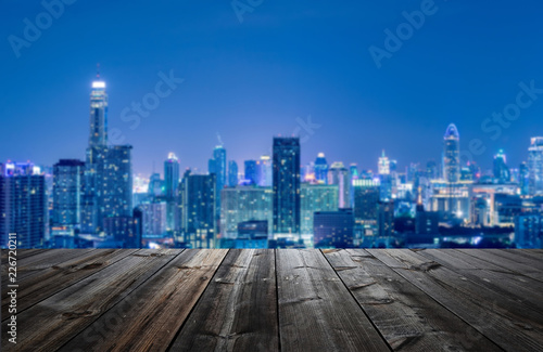 Blurred City skyline with wooden foreground for backdrop. © newroadboy