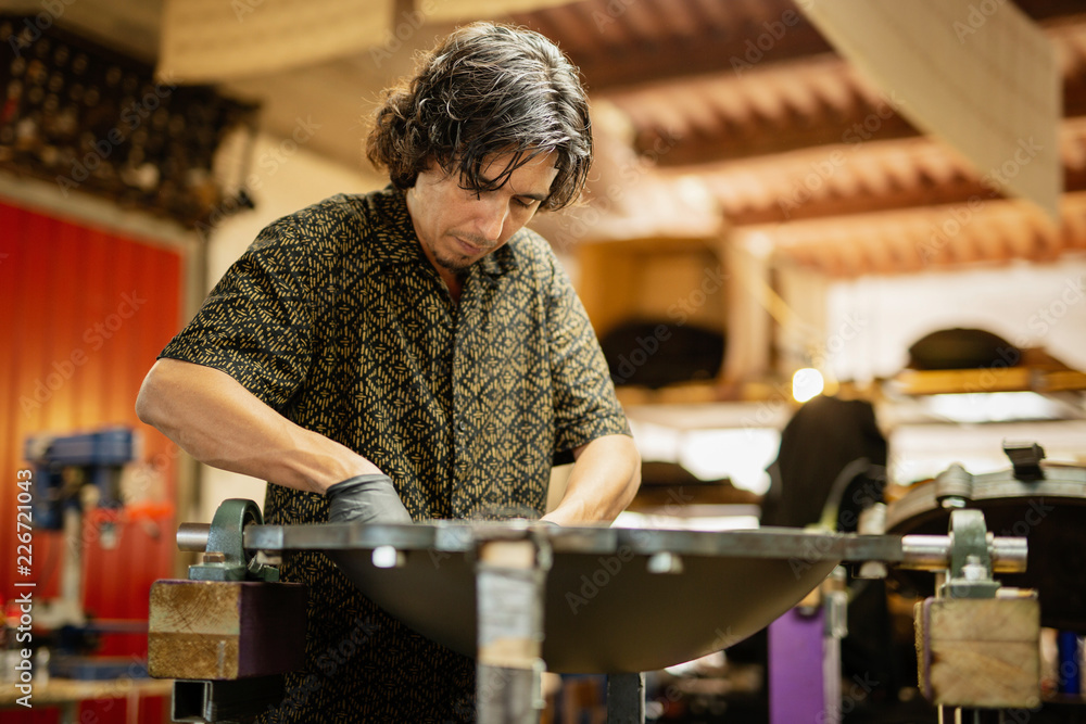 Craftsman in his workshop making design and construction of Handpan, a metal percussion instrument. Craftsman in his workshop making design and construction of Handpan, a metal percussion instrument.