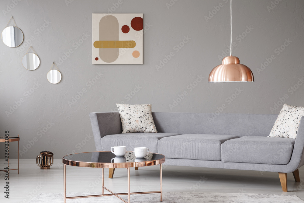 Copper lamp and coffee table in front of a modern sofa in a grey living ...