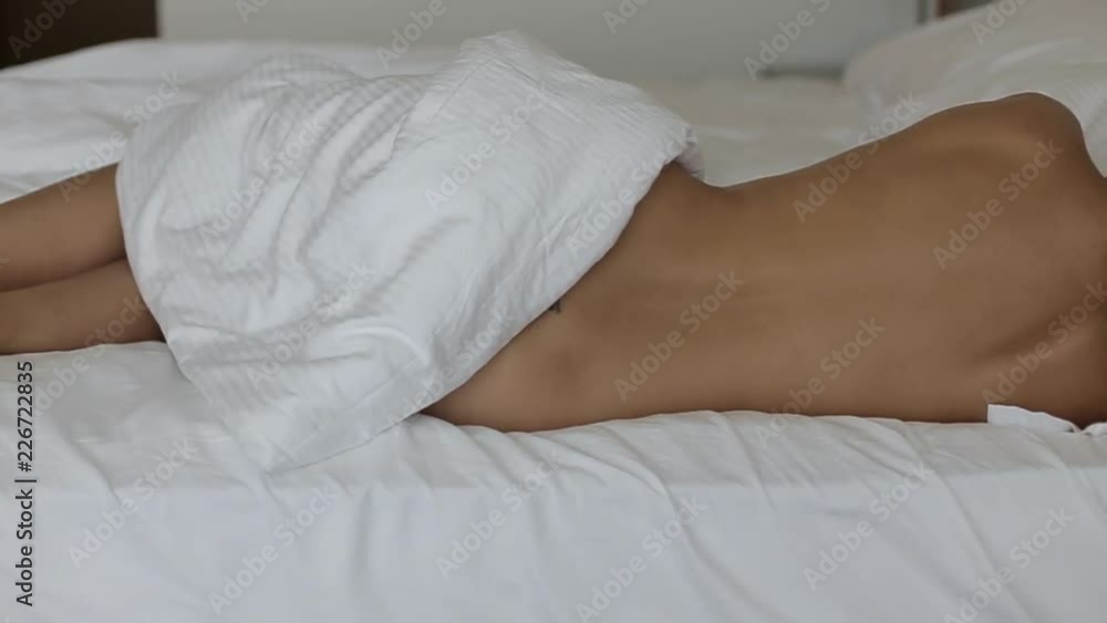 Back view of back and legs of naked young woman with long blonde hair covered with blanket Back view of back and legs of naked young woman with long blonde hair covered with blanket