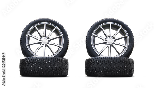 Four new good-looking snow tires isolated on the white background. A set of studded winter car tires. A set of wheels and tyre packages. Winter wheel parts photo