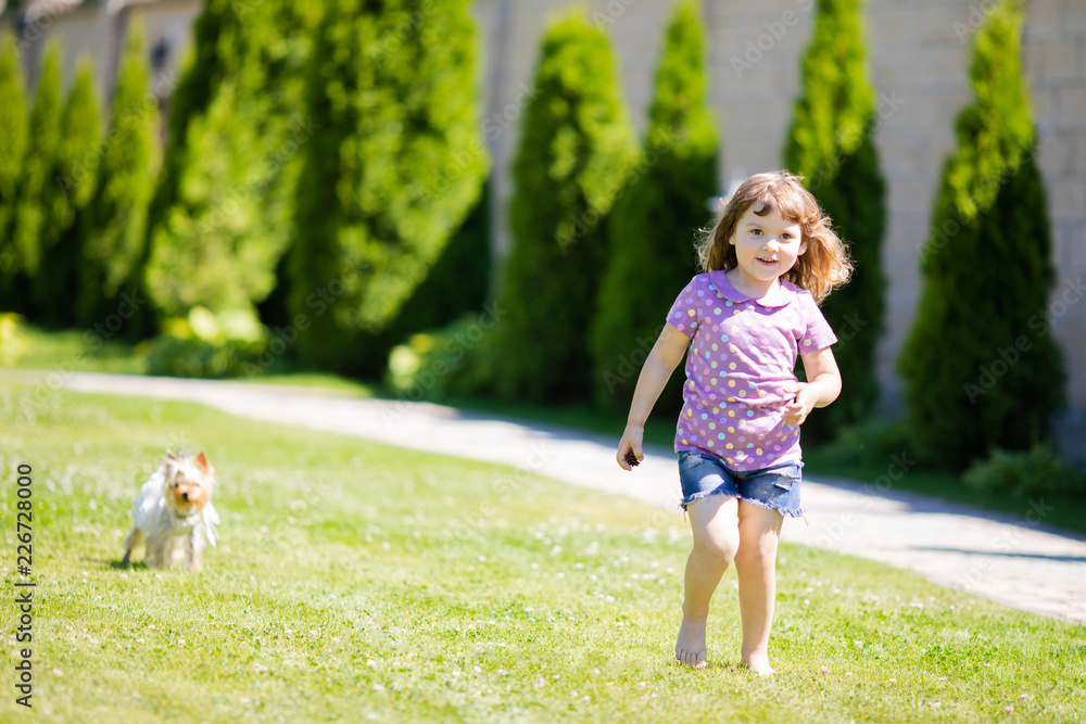 Cute little girl playing and running with small dog (terrier) outdoors Cute little girl playing and running with small dog (terrier) outdoors