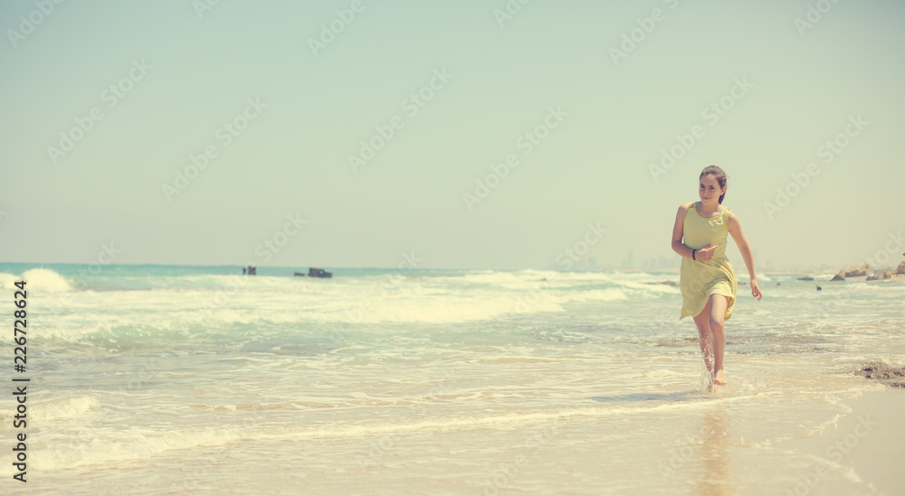 12 years old girl teen girl in yellow dress walking on seaside. Summer vacation 12 years old girl teen girl in yellow dress walking on seaside. Summer vacation