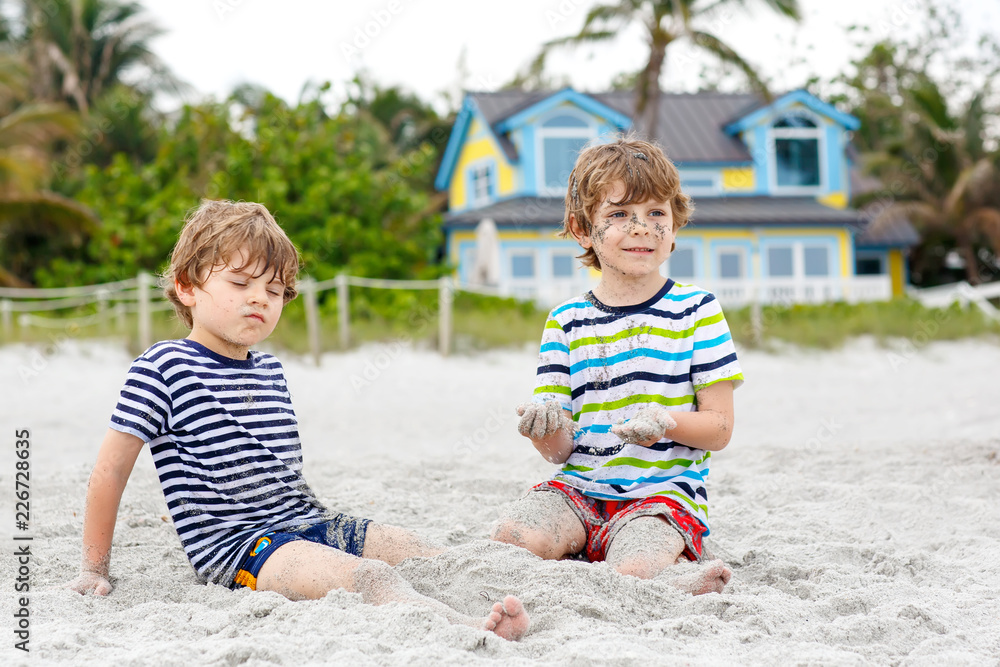 Two little kids boys having fun with building sand castle on tropical beach Two little kids boys having fun with building sand castle on tropical beach