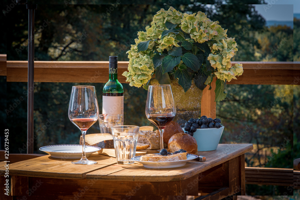old wooden table with wine, bread and cheese in summer
