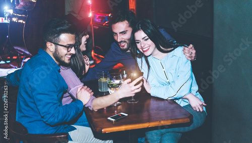 Photography Happy friends using mobile phones in jazz cocktail bar