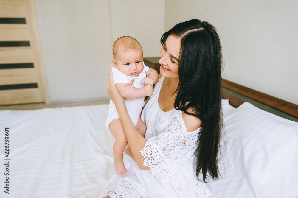 Fototapeta premium happy young mother carrying her little child while sitting on bed at home