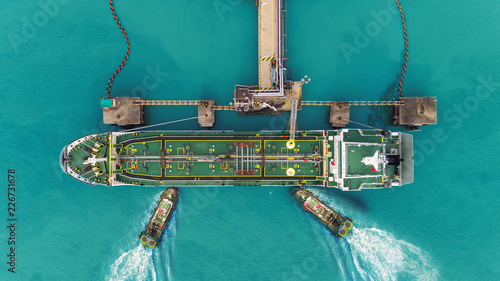 Tug boats drag Oil ship tanker park to port for transfer crude oil to oil refinery.