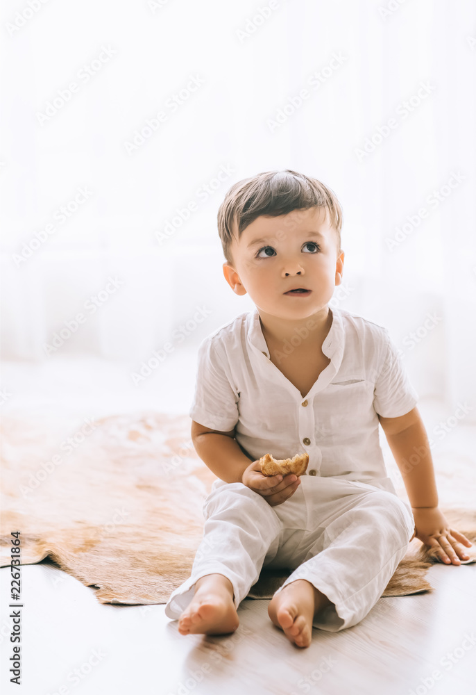 adorable little kid sitting on floor and eating cookie adorable little kid sitting on floor and eating cookie