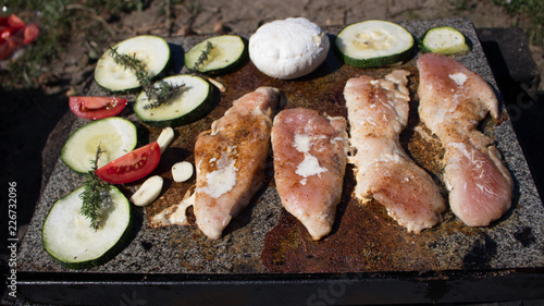 Grilling chicken breast and vegetables on the stone, hot meat dishes