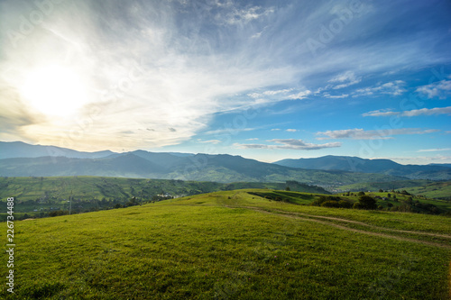 Meadows with horses, a village and a view of the mountains (Ukrainian Carpathians). Sunset landscape with beautiful clouds © mizinra