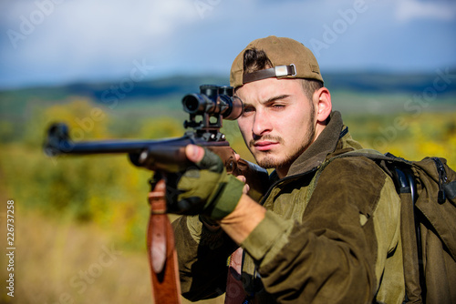 Guy hunting nature environment. Hunting weapon gun or rifle. Man hunter aiming rifle nature background. Hunting skills and weapon equipment. Hunting target. Looking at target through sniper scope