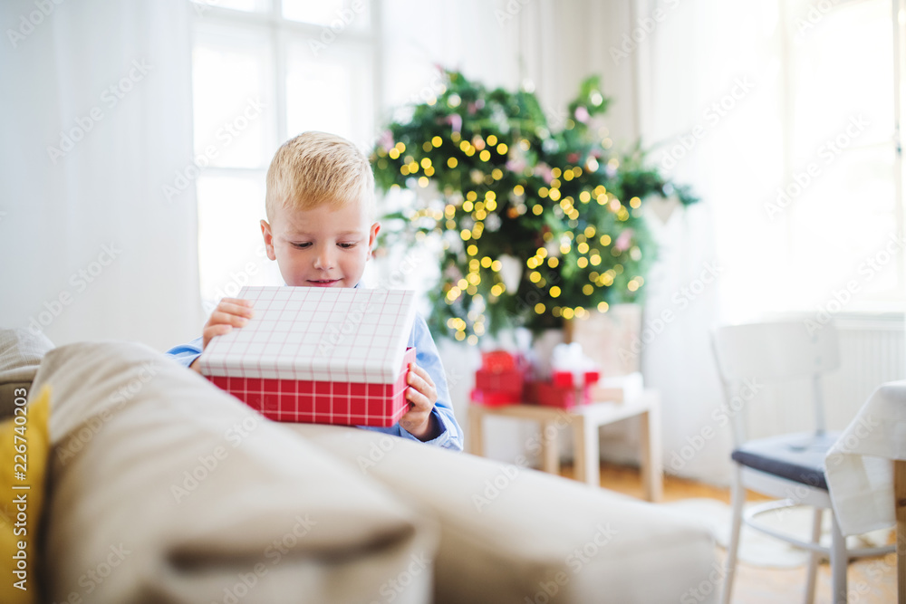 A small boy with opening up a present at home at Christmas time. A small boy with opening up a present at home at Christmas time.