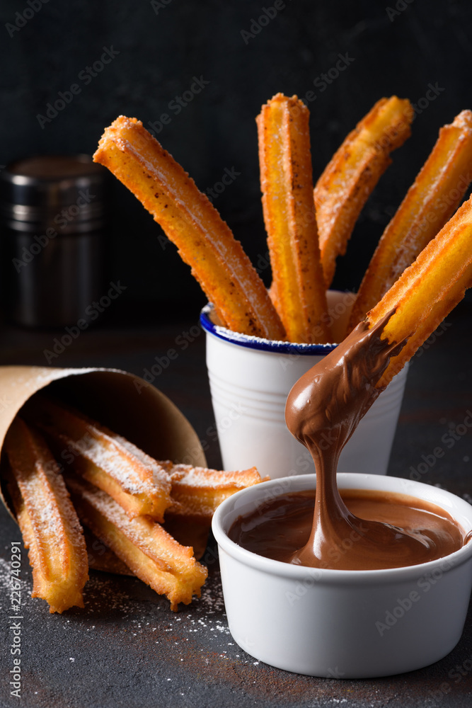 Ταπετσαρία Churro with sugar powder and cinnamon in melted chocolate dip