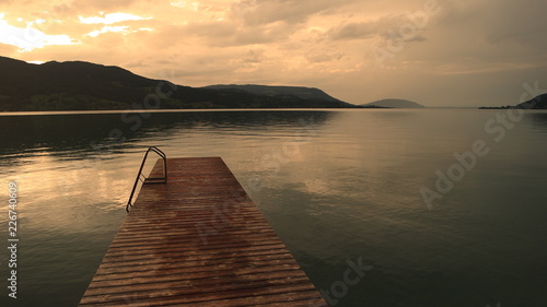 Fototapeta Naklejka Na Ścianę i Meble -  Long old wooden jetty deck background and beautiful sunset