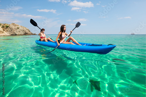 Two young women kayaking in the sea. Beautiful woman canoeing on the island on a summer day.