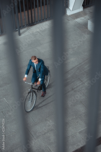 high angle view of businessman in formal wear riding bicycle and looking away on street