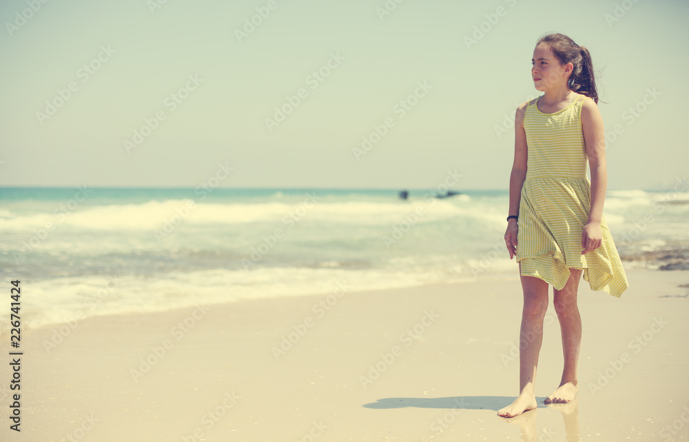 12 years old girl teen girl in yellow dress walking on seaside. Summer vacation 12 years old girl teen girl in yellow dress walking on seaside. Summer vacation