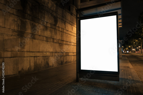 Light box with white blank space for ads at bus stop and wall in background. Night street marketing concept. Horizontal mock-up