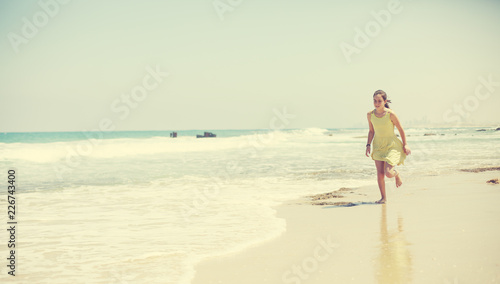 12 years old girl teen girl in yellow dress walking on seaside. Summer vacation