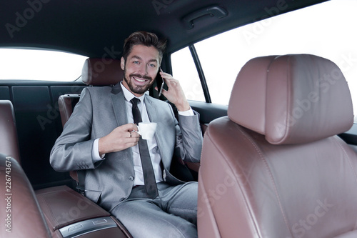 businessman sitting in car with cup and smartphone © ASDF