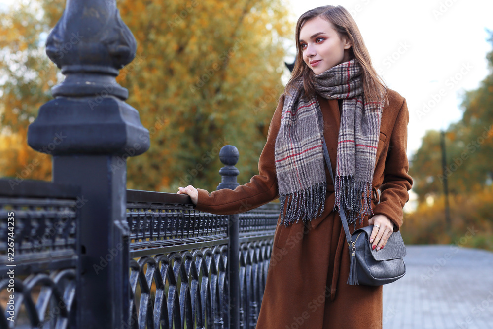 Fashion young woman outdoor. Wearing coat, scarf, and handbag Fashion young woman outdoor. Wearing coat, scarf, and handbag