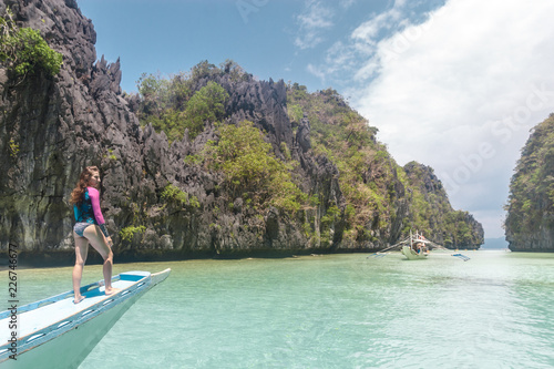 Woman relaxing on the boat and looking forward into lagoon. Travelling tour in Asia: El Nido, Palawan, Philippines.