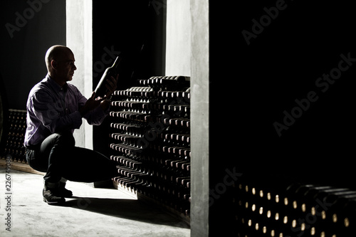 Wine maker checking bottles in a dark cellar