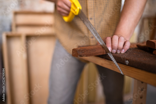 Carpenter saws a board with a hand wood saw. Close-up look on the process of sawing a wooden blank