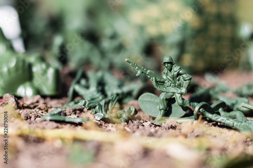 plastic toys. figures of small green armed soldiers fighting each other.