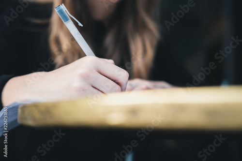 Closeup image of girl handwriting on piece of paper at table. Education concept. 