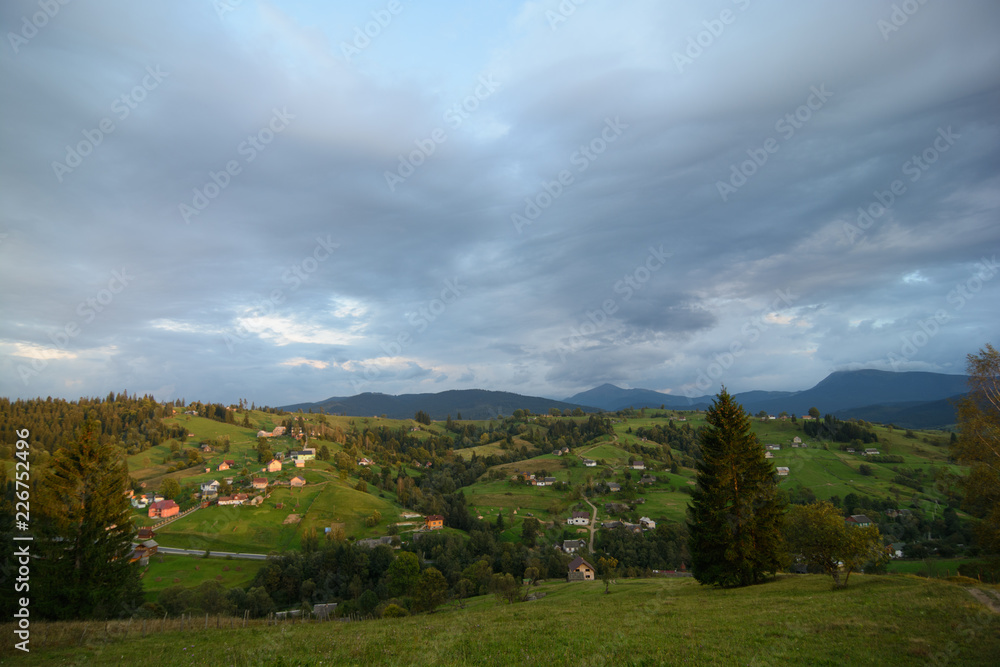 Landscape area (village houses, firs, pines, trees, mountains, hills, sunset). Nature and man. Natural background.