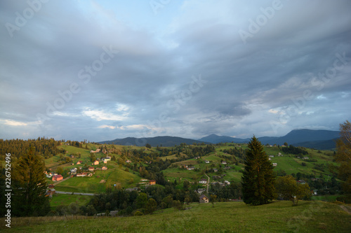 Landscape area (village houses, firs, pines, trees, mountains, hills, sunset). Nature and man. Natural background.