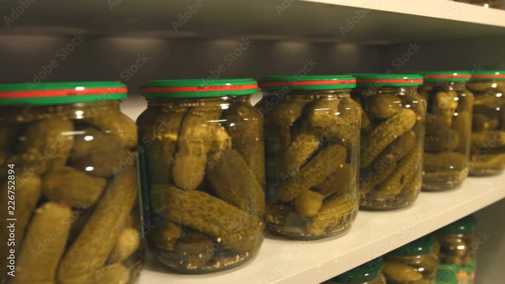 Pickled cucumbers in banks stand on the shelf in store. Pickled