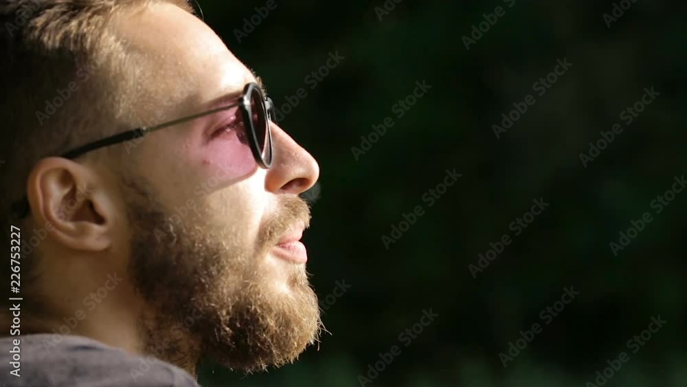 Man in glasses smoking a cigarette in nature. Close up shot of man's hand and mouth. Closeup shot of a man's face Man in glasses smoking a cigarette in nature. Close up shot of man's hand and mouth. Closeup shot of a man's face