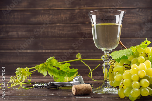 wine glass and bunch of grapes on wooden table