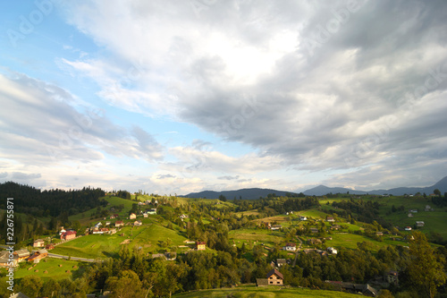 Landscape area (village houses, firs, pines, trees, mountains, hills, sunset). Nature and man. Natural background.