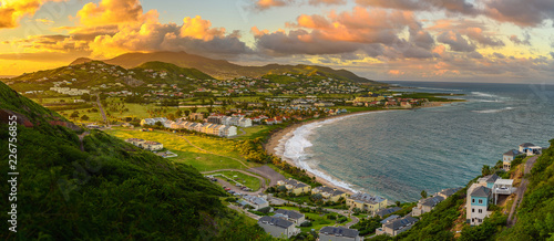 Fototapeta Naklejka Na Ścianę i Meble -  Panorama of Saint Kitts and its capital Basseterre during sunset, beautiful green mountains and a beach in paradise caribbean island with amazing green and orange colors. Saint kitts and nevis