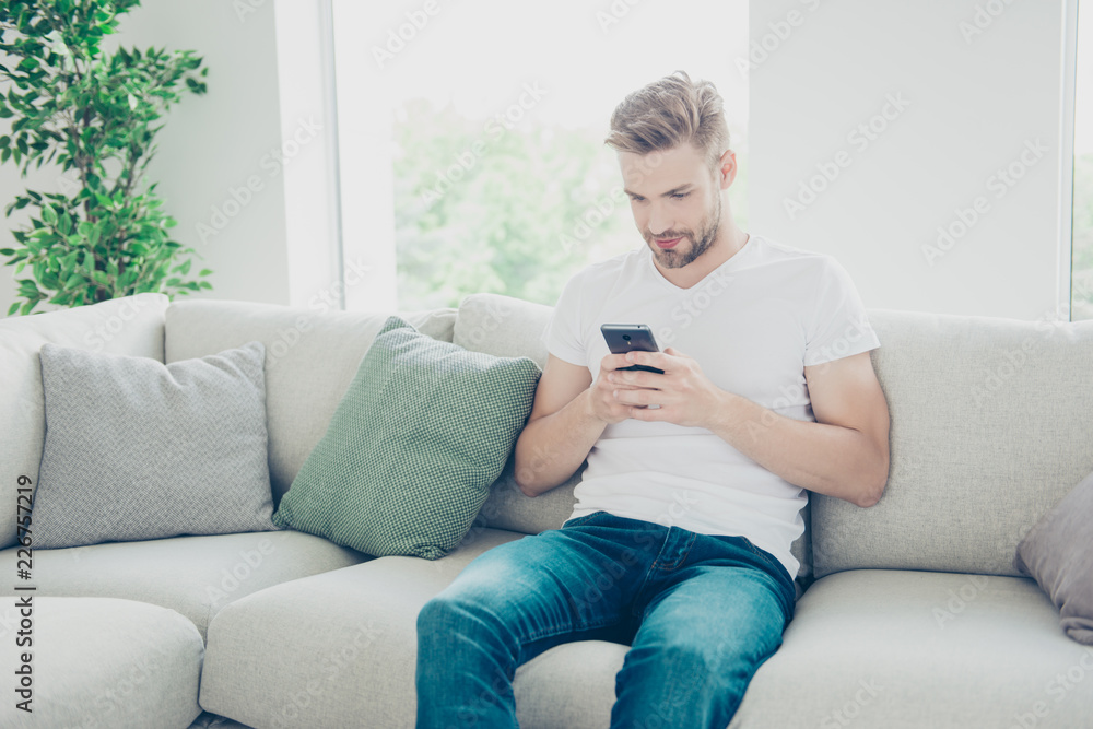 Portrait of brunet bristle man in bright white interior hold mod Portrait of brunet bristle man in bright white interior hold mod