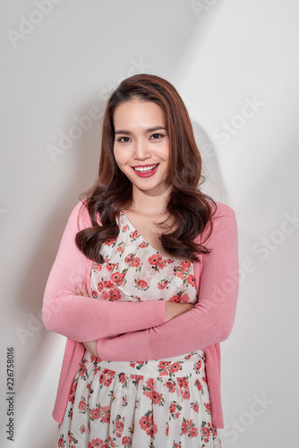 Fashion photo of a beautiful young woman in a pretty dress with flowers posing over white background