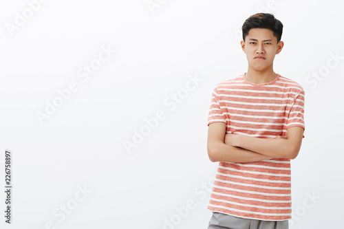 Canvas Print Young cute chinese guy in striped t-shirt looking offended and mad, keeping insu